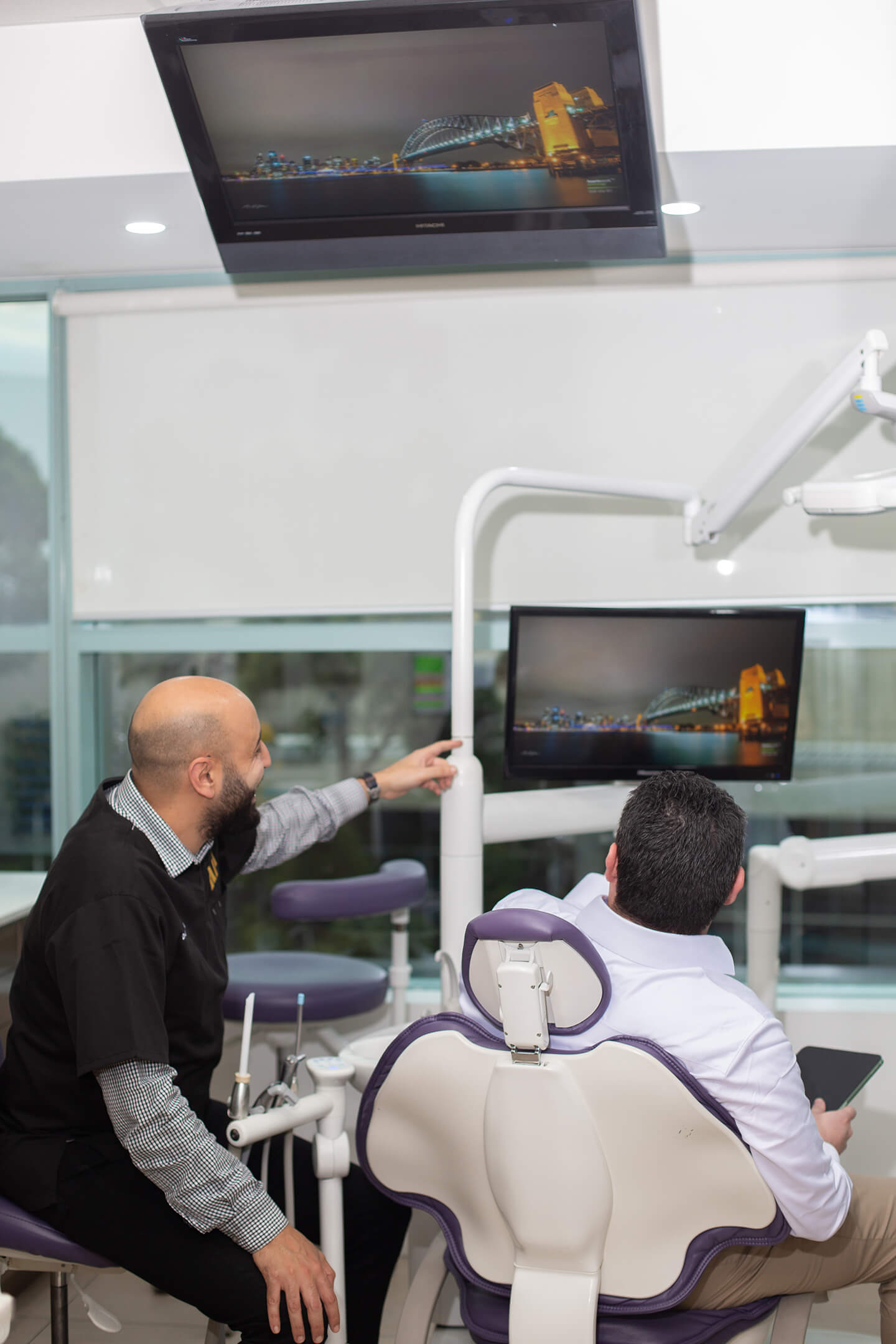 A dentist and a dental IT support technician in a clinic look at a screen.